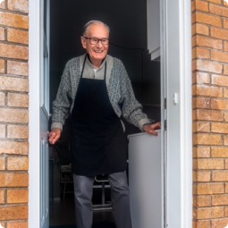 old man smiling by open door